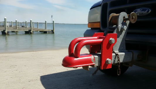 Red heavy-duty trailer lock securing a trailer coupler at a boat ramp
